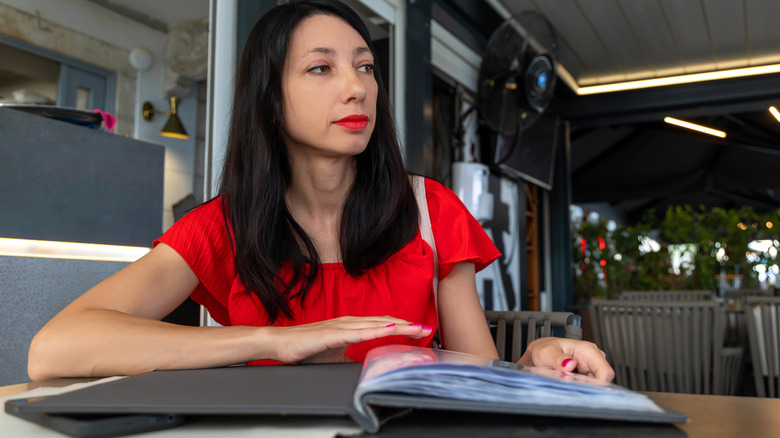 Woman waits to order at a restaurant with menu in hand