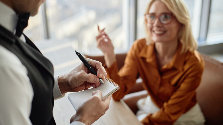 Woman orders food while server writes it down