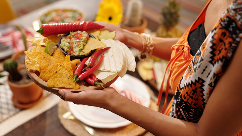 Woman carries tray with Mexican appetizers and peppers