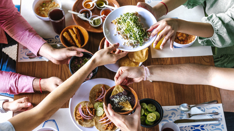 Diners pass dishes over a table at a Mexican restaurant