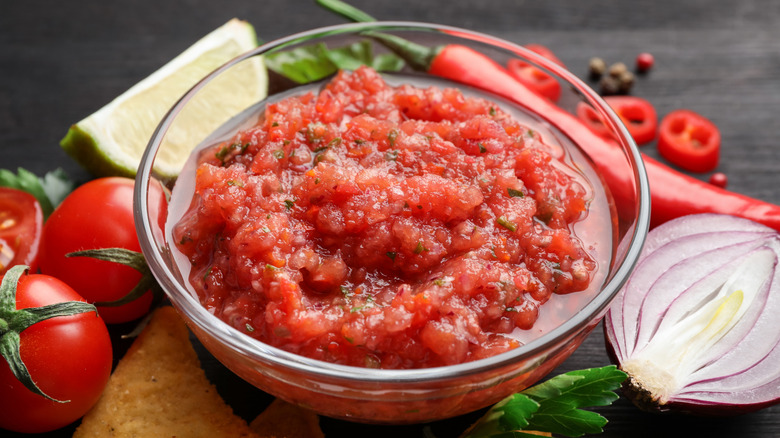 Glass ramekin with salsa surrounded by ingredients