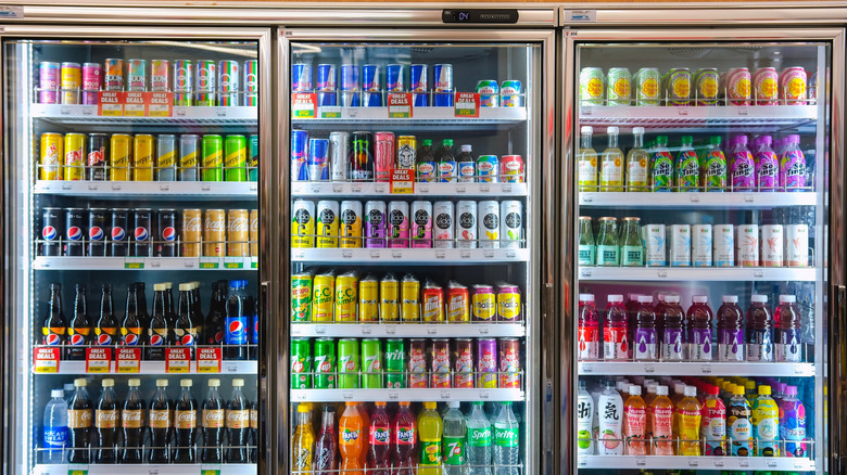 Variety of energy drinks, soda, soft drinks, fruit juice, non-carbonated, in bottles and cans on store shelves.