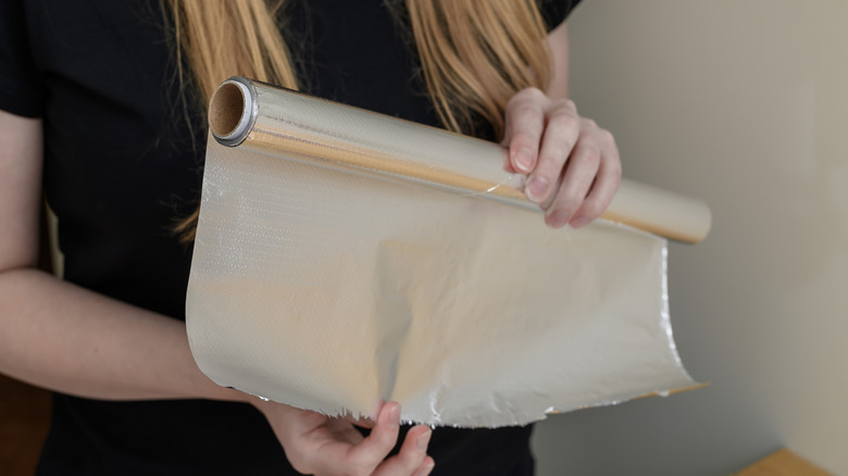 A woman unrolling a spool of tinfoil