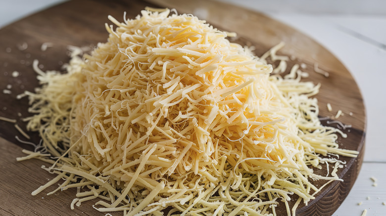 A pile of grated cheese on a wooden board