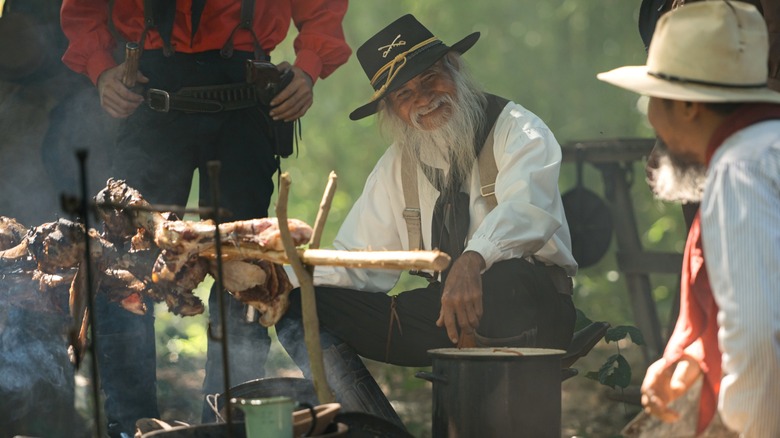 Cowboys sitting around campfire with meat roasting