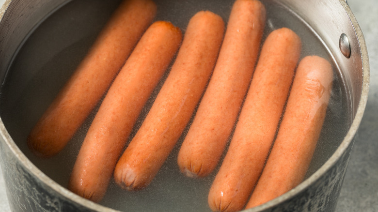 Several hot dogs floating in a pot of water