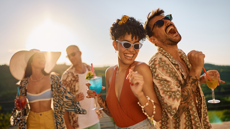 Friends dancing with drinks in the late afternoon summer sun