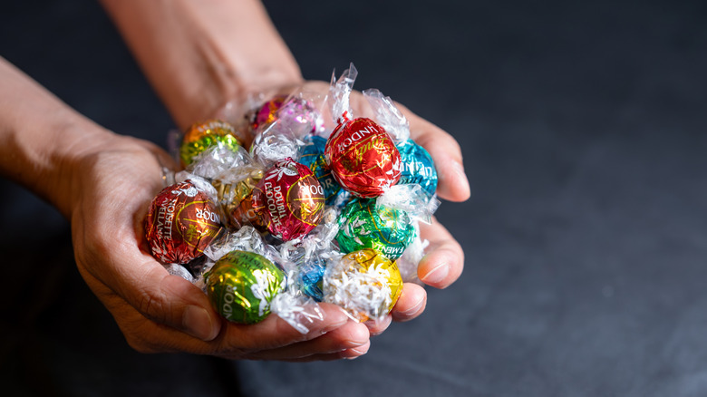 Hands holding handful of Lindt Lindor chocolate truffles