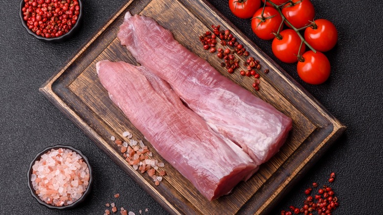 Raw pork tenderloin on wood board