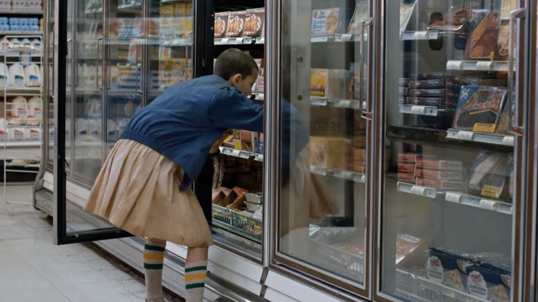 The character Eleven from Stranger Things reaches into freezer display