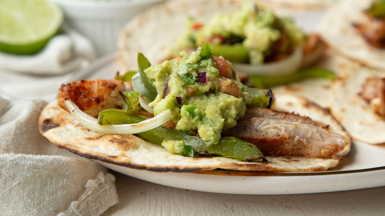 chicken, vegetables, and guacamole on a flour tortilla