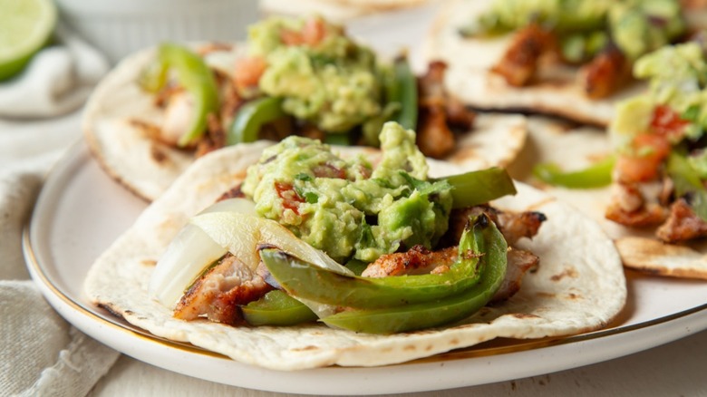 chicken, vegetables, and guacamole on a flour tortilla
