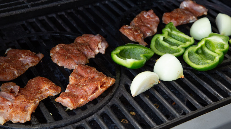 chicken thighs, green peppers, and onions on a grill