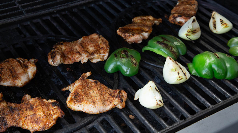 chicken thighs, green peppers, and onions on a grill