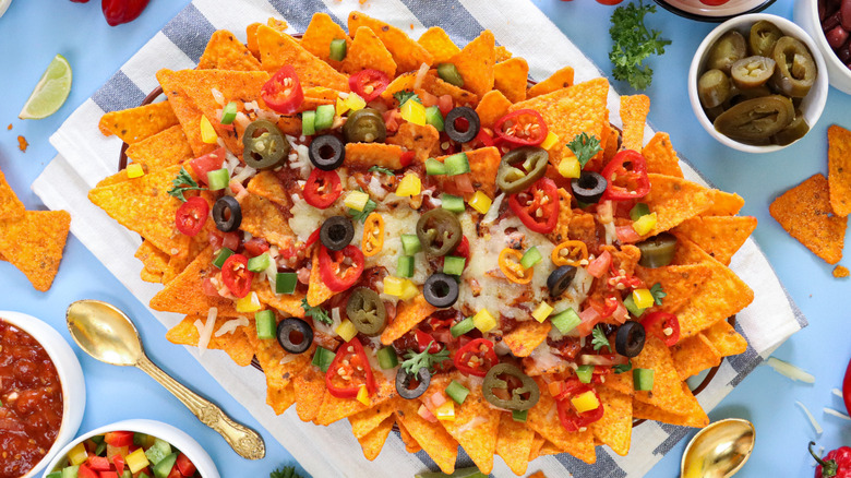 Close-up on nachos with peppers, jalapeños, cheese, and black olives