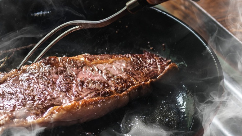 Close-up of a steak sizzling in a pan