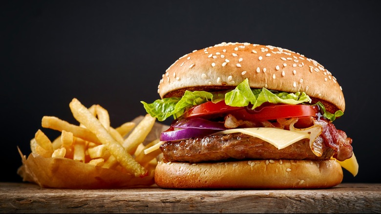 Burger and fries on wood board with dark background