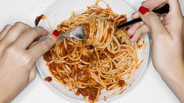 Hands spin spaghetti pasta on a fork