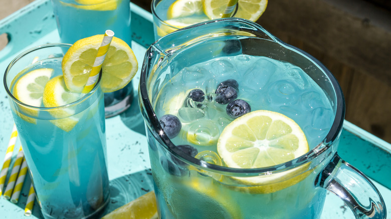 A pitcher and glasses filled with electric lemonade.