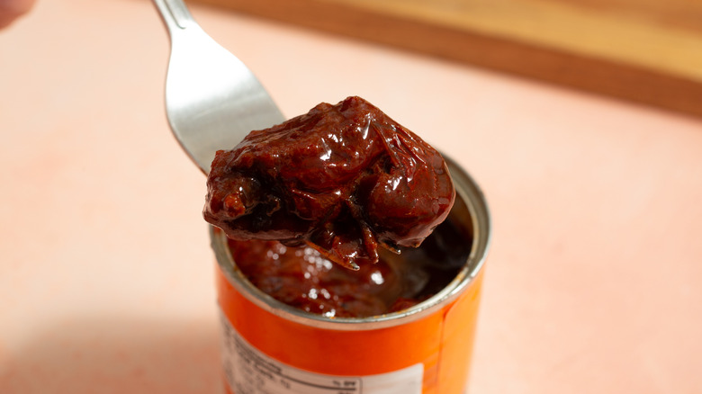 Top view of a fork picking up a canned chipotle chile