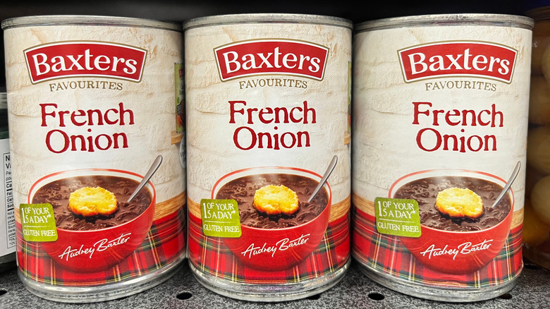 Cans of Baxters French onion soup on display on a grocery store shelf.