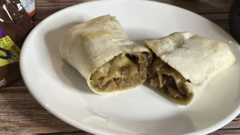 Frozen beef and bean burrito cut in half on a white plate.