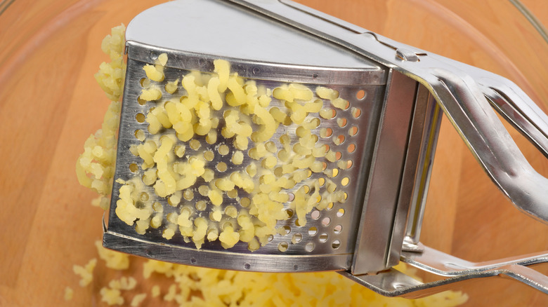 potato ricer pushing potatoes out the holes