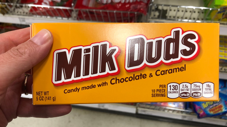 Hand holding box of Milk Duds candies