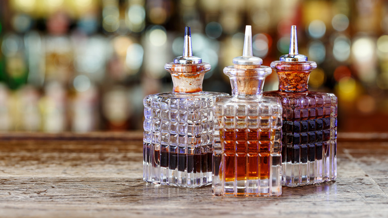 Three glass dripper bottles filled with bitters for cocktails