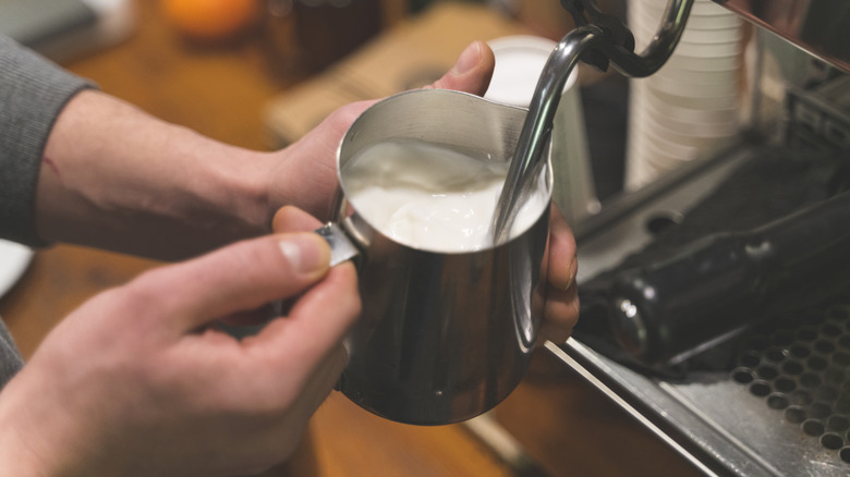 A barista steams milk with a clean steam wand