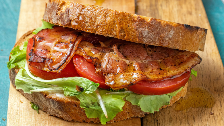 A bacon, tomato, and lettuce sandwich on a wooden board
