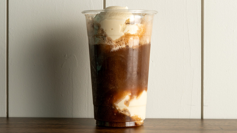 A plastic cup with soda and scoops of ice cream in it