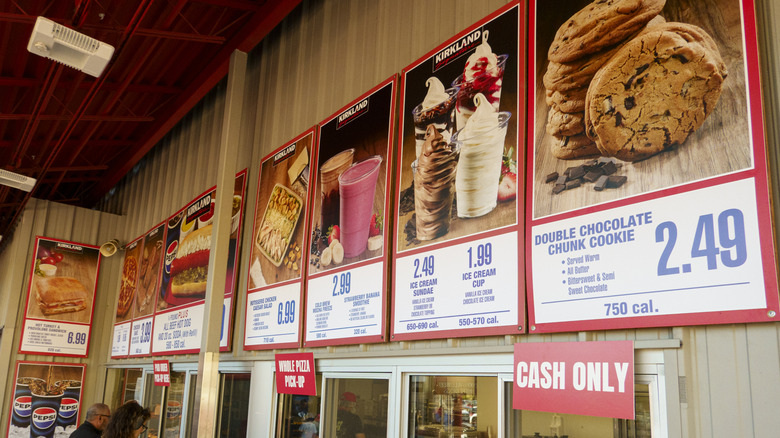 An outdoor Costco food court with signs showcasing each of its menu items