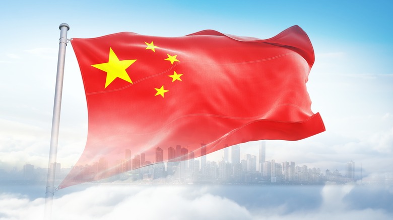 Chinese flag waving in front of cityscape and clouds
