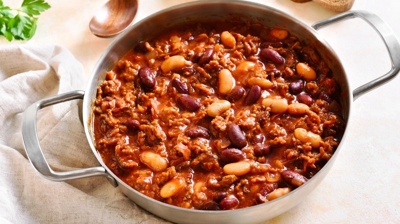 Cowboy beans in a steel pot sitting on a dish rag.