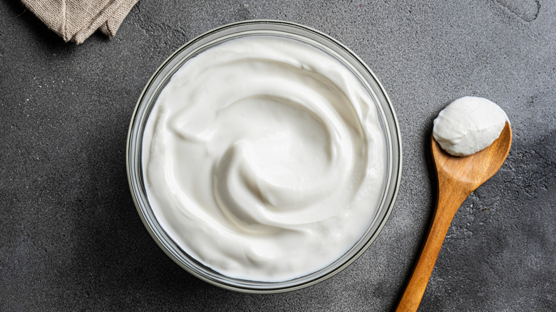 Homemade yogurt in a bowl with a wooden spoon beside it.