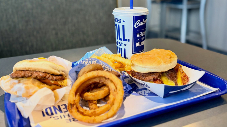ButterBurgers, onion rings, fries, and drink from Culver's on blue tray.