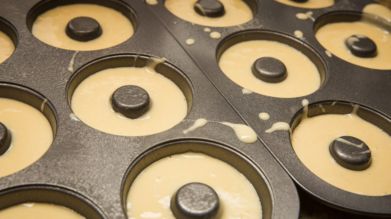 A closeup of metal donut molds filled with batter