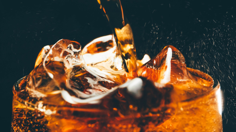 Cola pours into a glass with ice
