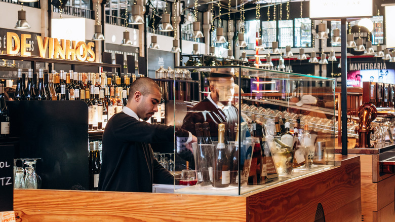 A bartender opens a bottle of wine at a bar at Time Out Market