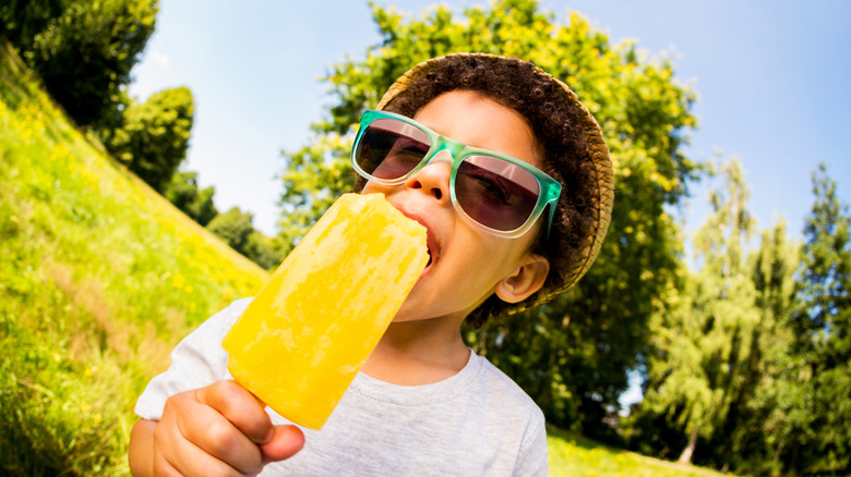 Kid eating a popsicle in the summertime