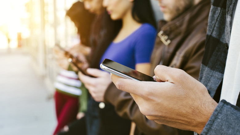 Line of people looking at their phones