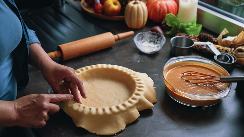 Hands pressing pie dough into pan