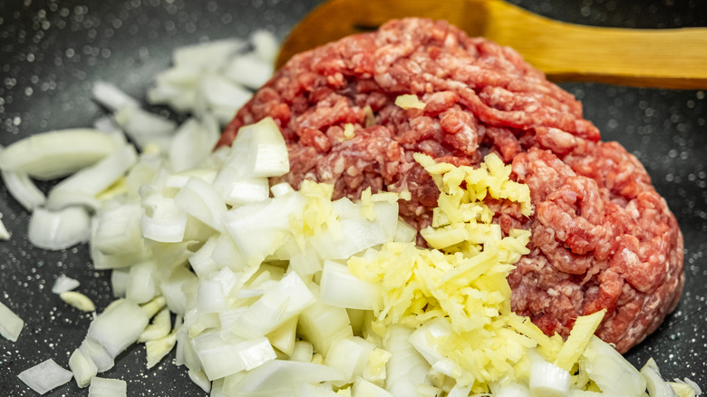 Onions and ground beef on a dark surface