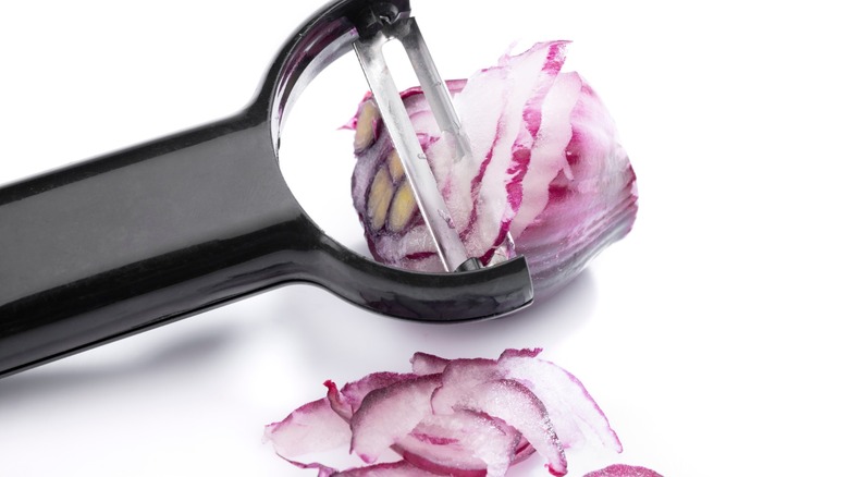 Vegetable peeler slicing onion up close
