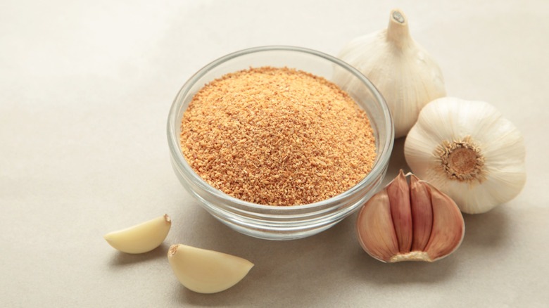 Fresh garlic cloves and small glass bowl of granulated garlic