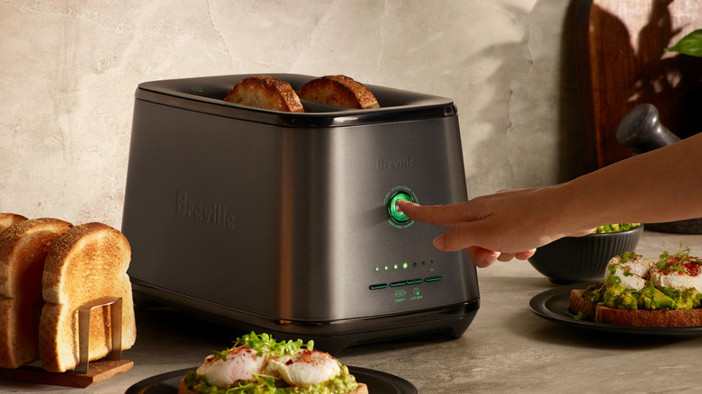 A hand pressing the main button on the Breville Eye Q toaster