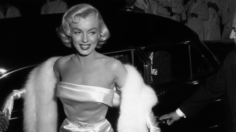 Marilyn Monroe stepping out of a car at a film premiere.