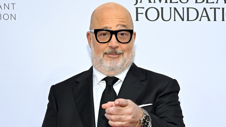 Andrew Zimmern in glasses, pointing at camera