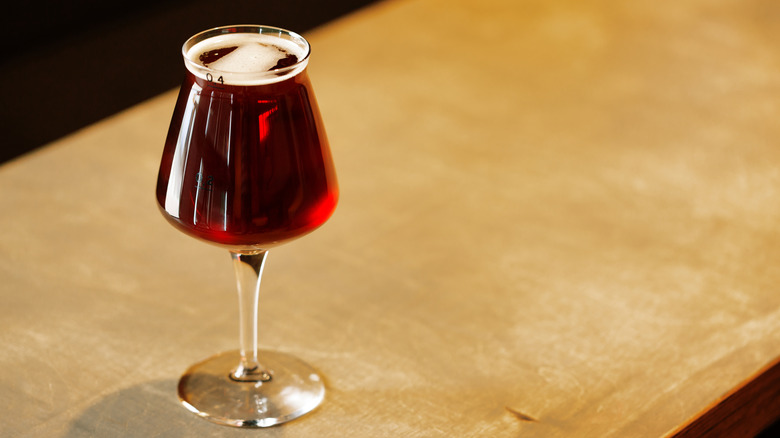 A Teku glass full of an amber beer